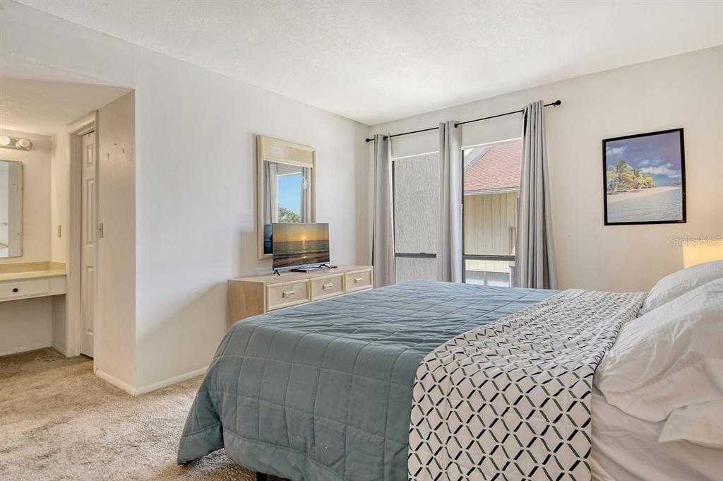 6157 Midnight Pass Road, Unit E63 Sarasota, FL 34242 - Photo 23 of 61 a bedroom with a bed and a flat screen tv