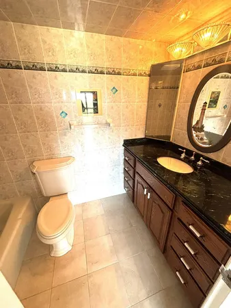 a bathroom with a granite countertop toilet sink and mirror