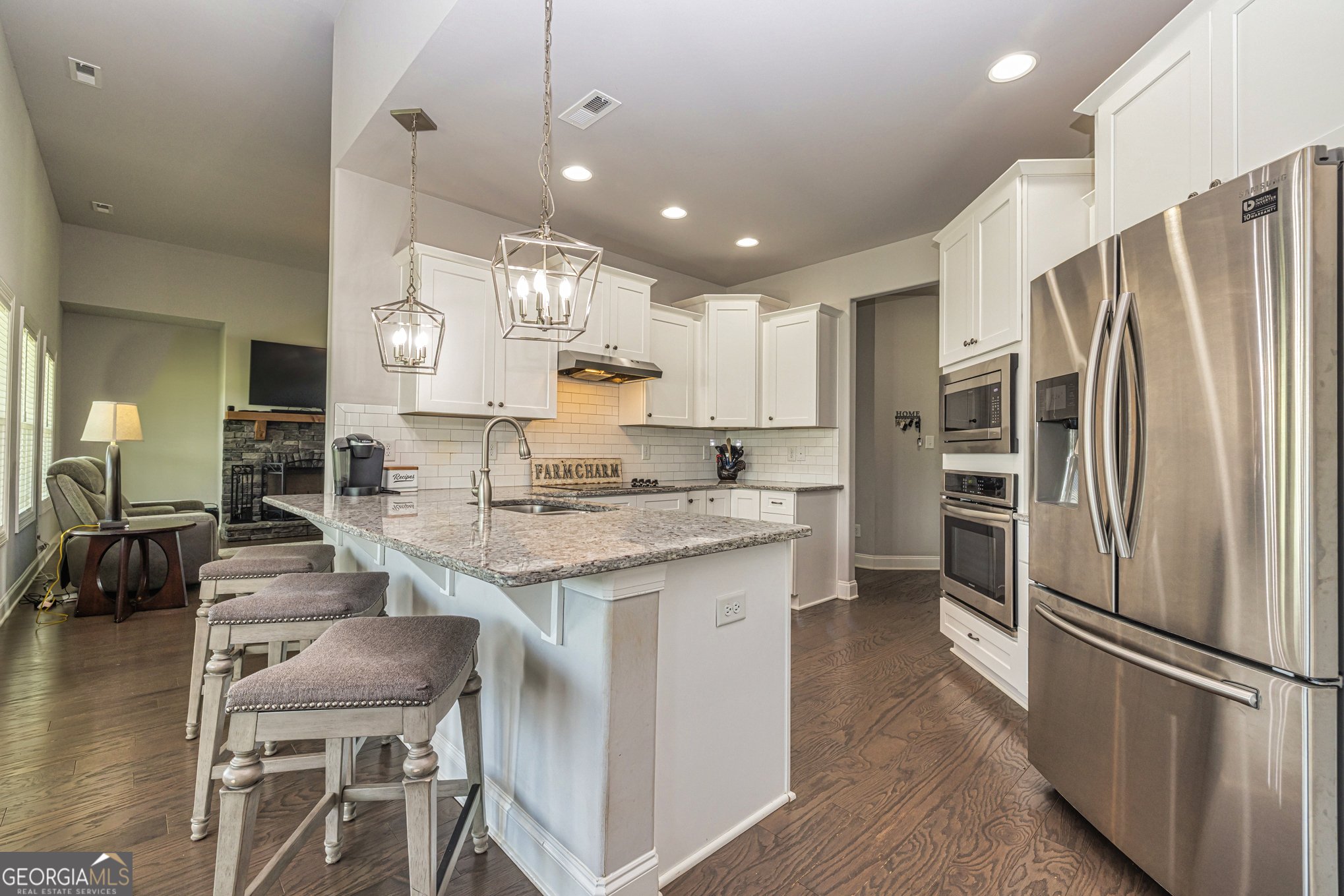 941 Highway 16 Newnan, GA 30263 - Photo 13 of 43 a kitchen with kitchen island granite countertop a refrigerator a stove a sink a dining table and chairs with wooden floor