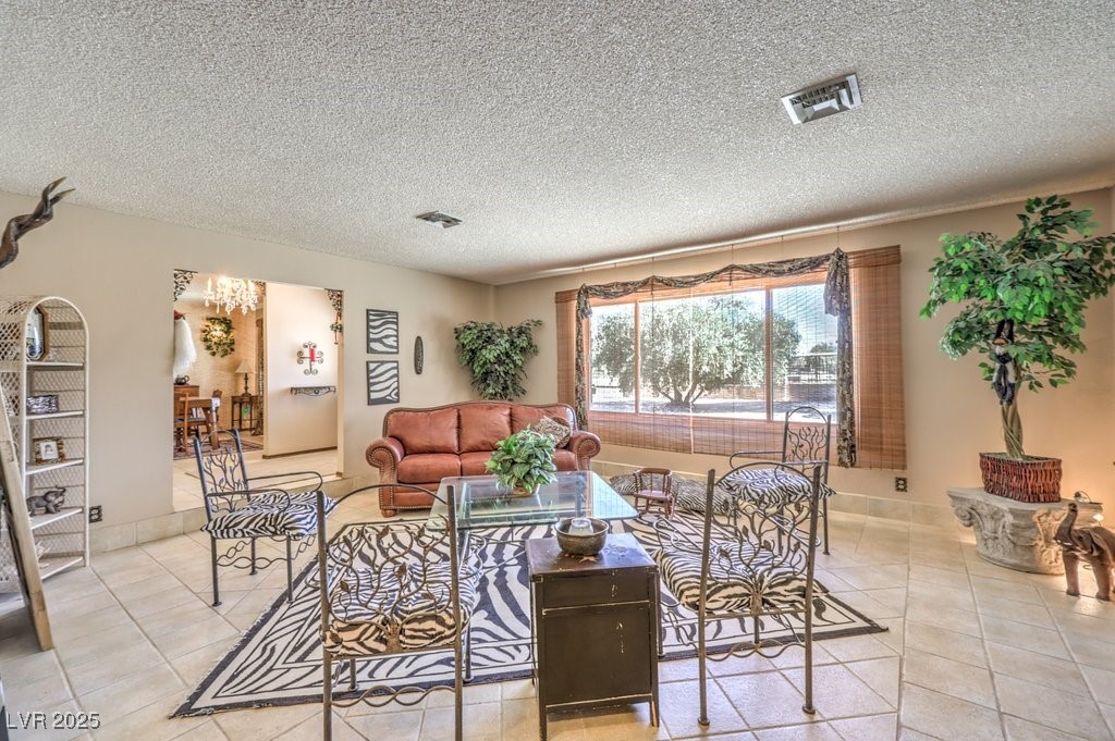 10615 Rancho Destino Road Las Vegas, NV 89183 - Photo 11 of 53 Living room with light tile patterned floors, visible vents, and a textured ceiling