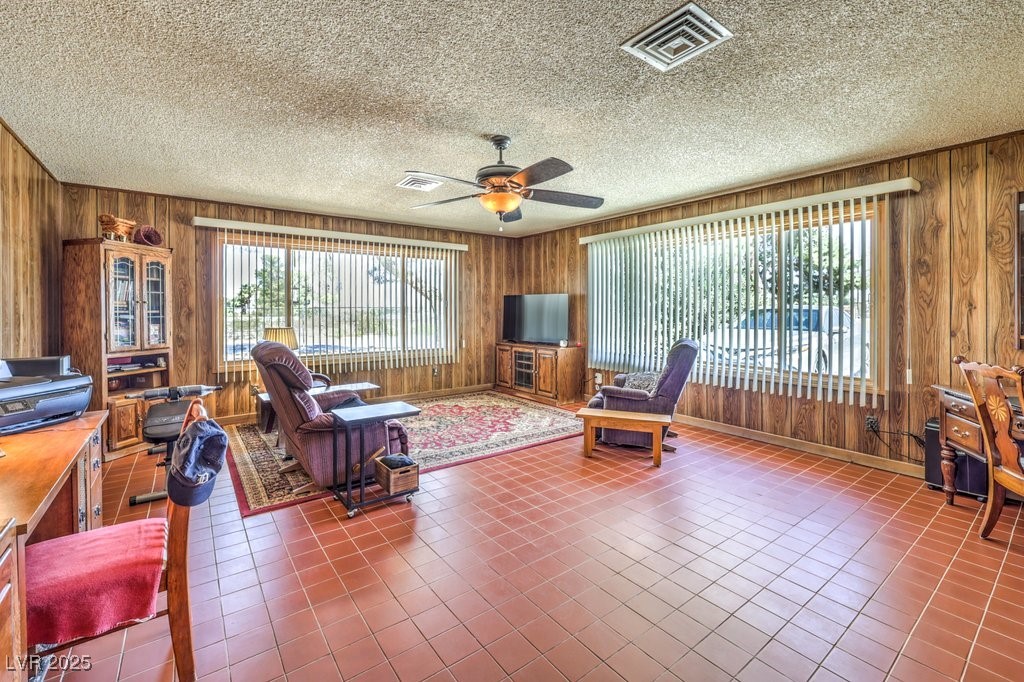 10615 Rancho Destino Road Las Vegas, NV 89183 - Photo 23 of 53 Tiled living area featuring a ceiling fan, wooden walls, a healthy amount of sunlight, and visible vents