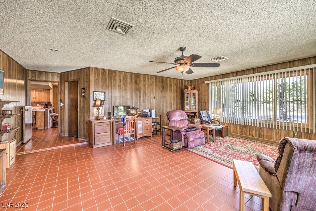10615 Rancho Destino Road Las Vegas, NV 89183 - Photo 24 of 53 Living area featuring visible vents, wood walls, and a ceiling fan