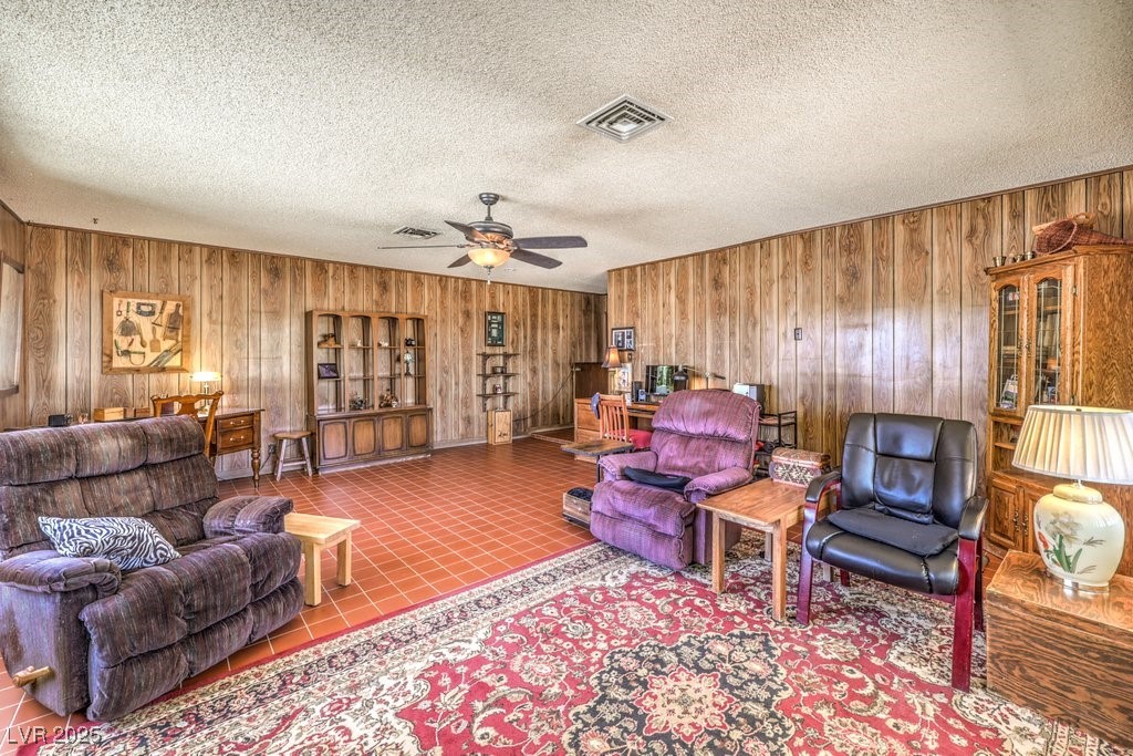 10615 Rancho Destino Road Las Vegas, NV 89183 - Photo 25 of 53 Tiled living room with a ceiling fan, visible vents, wood walls, and a textured ceiling