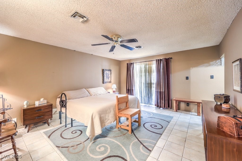 10615 Rancho Destino Road Las Vegas, NV 89183 - Photo 26 of 53 Bedroom with light tile patterned floors, visible vents, a textured ceiling, and ceiling fan