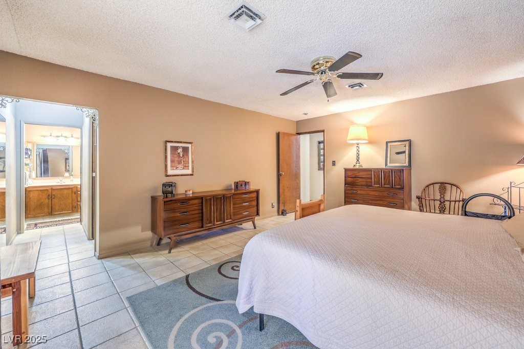 10615 Rancho Destino Road Las Vegas, NV 89183 - Photo 28 of 53 Bedroom with ceiling fan, light tile patterned floors, visible vents, and a textured ceiling