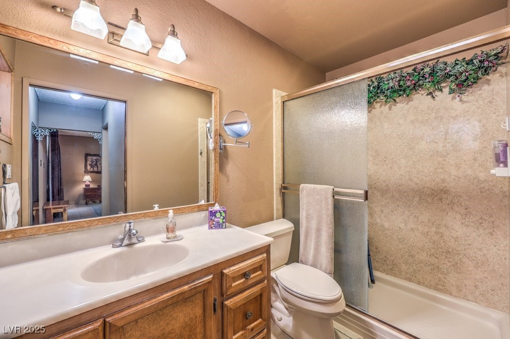 10615 Rancho Destino Road Las Vegas, NV 89183 - Photo 29 of 53 Full bath featuring a shower stall, toilet, vanity, and a textured wall