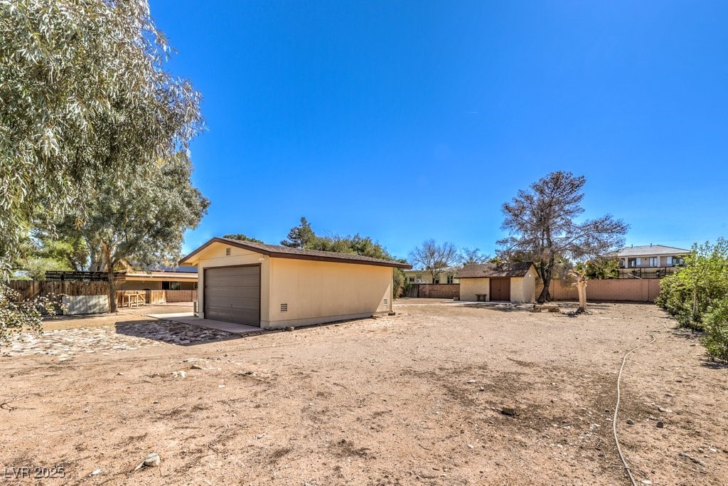 10615 Rancho Destino Road Las Vegas, NV 89183 - Photo 39 of 53 View of yard featuring a garage, an outdoor structure, and fence