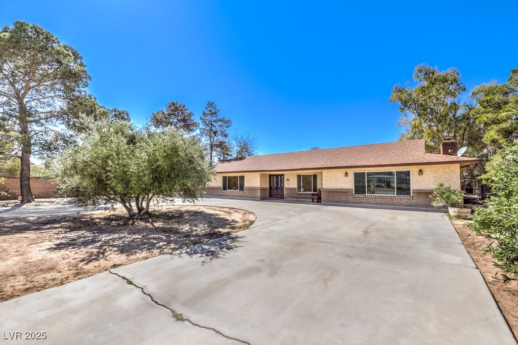 10615 Rancho Destino Road Las Vegas, NV 89183 - Photo 4 of 53 Ranch-style home with stucco siding, brick siding, a chimney, and a shingled roof