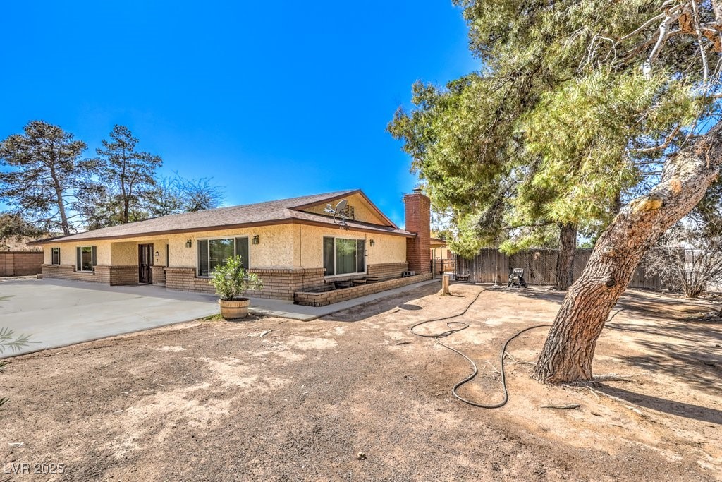 10615 Rancho Destino Road Las Vegas, NV 89183 - Photo 5 of 53 Rear view of house with a patio, brick siding, a chimney, and fence