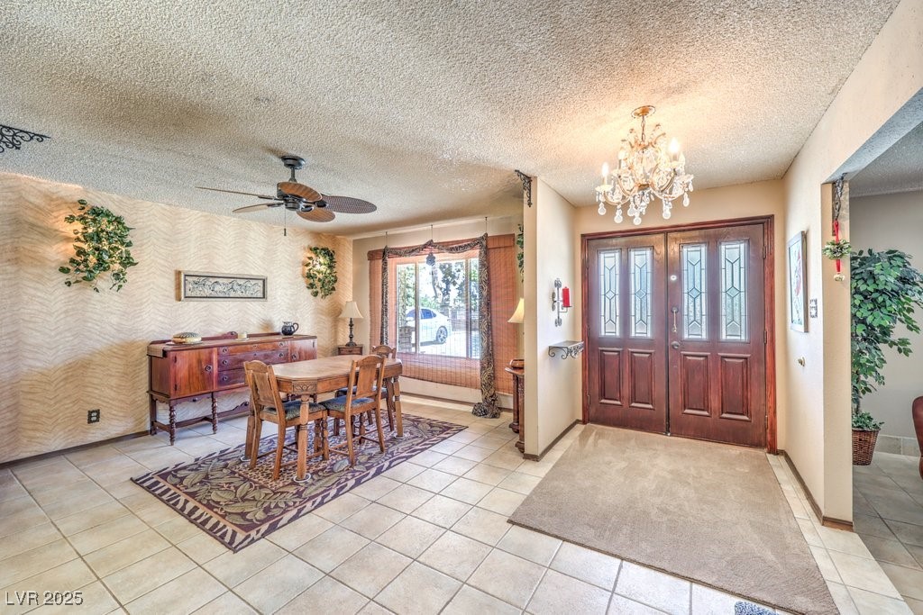 10615 Rancho Destino Road Las Vegas, NV 89183 - Photo 7 of 53 Foyer featuring light tile patterned floors, baseboards, a textured ceiling, and ceiling fan with notable chandelier