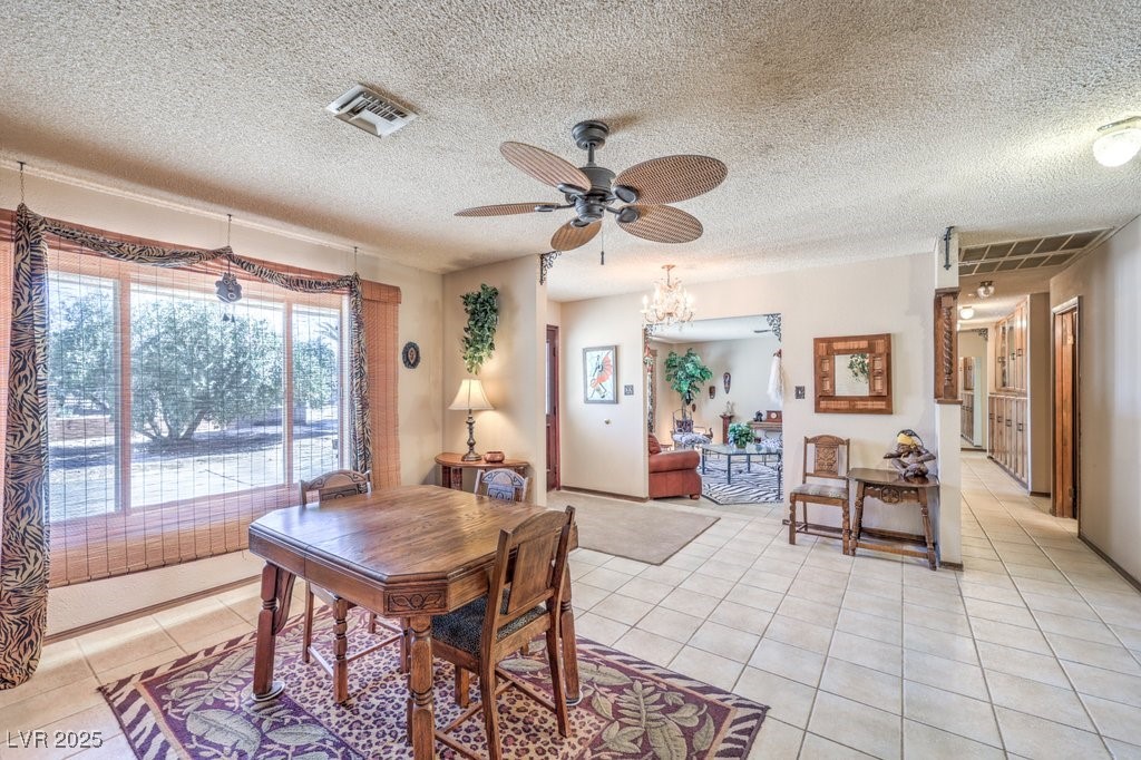 10615 Rancho Destino Road Las Vegas, NV 89183 - Photo 8 of 53 Dining area with light tile patterned flooring, ceiling fan with notable chandelier, visible vents, and a textured ceiling