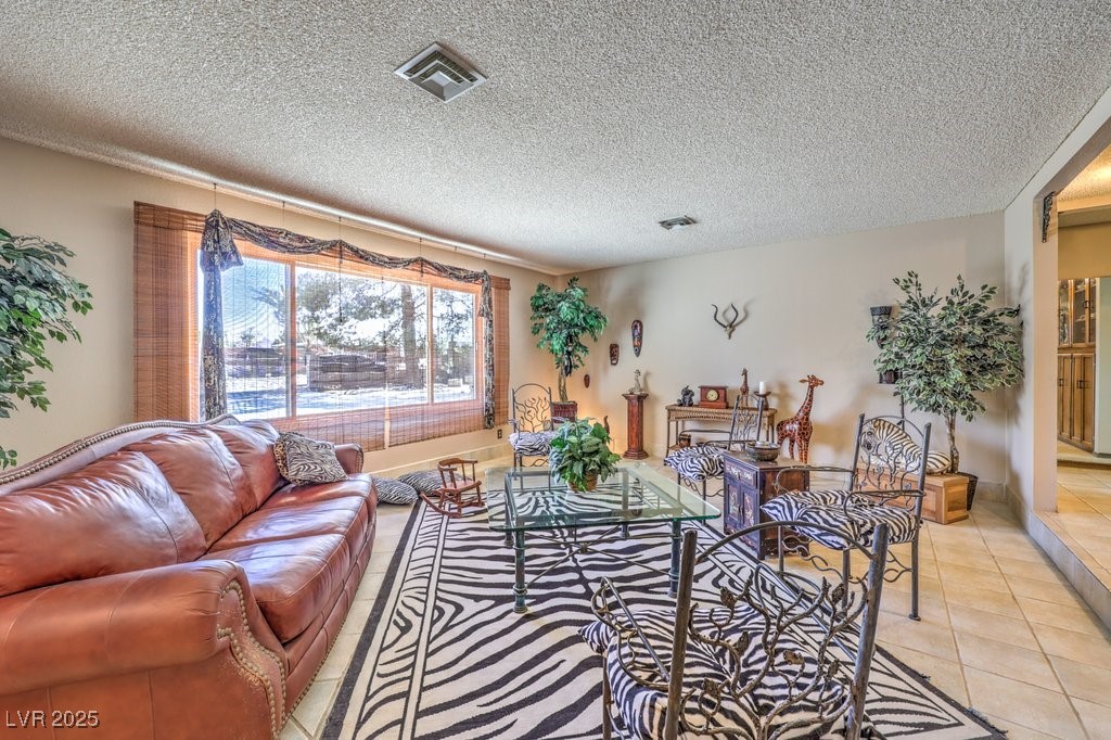 10615 Rancho Destino Road Las Vegas, NV 89183 - Photo 10 of 53 Living room featuring light tile patterned floors, visible vents, and a textured ceiling