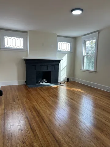 an empty room with windows a fireplace and wooden floor