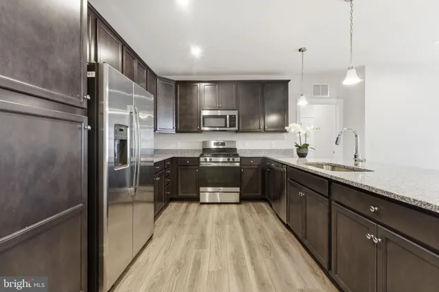 a large kitchen with a large counter top a sink stainless steel appliances and cabinets