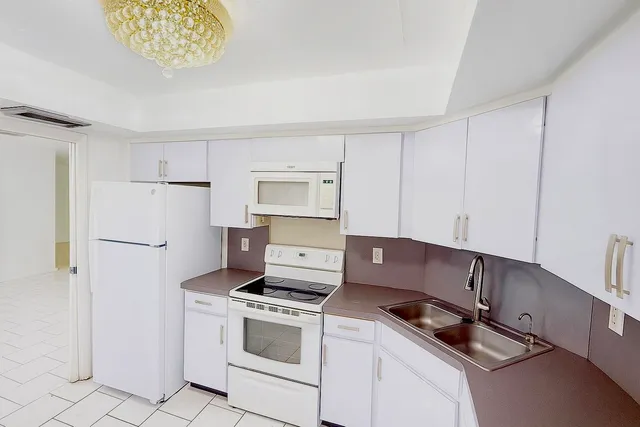 a kitchen with granite countertop white cabinets and white appliances