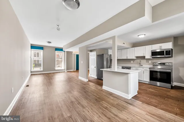 a view of kitchen with granite countertop a stove top oven a sink dishwasher a refrigerator and white cabinets with wooden floor