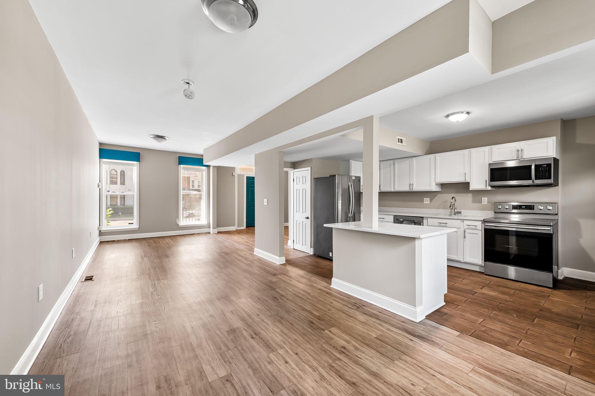 4021 Park Heights Avenue Baltimore, MD 21215 - Photo 2 of 32 a view of kitchen with granite countertop a stove top oven a sink dishwasher a refrigerator and white cabinets with wooden floor