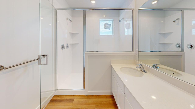 783 Pheasantbrook Drive, Unit 2A Centerville, UT 84014 - Photo 15 of 41 Modern bathroom featuring a double vanity with integrated sinks, a large mirror, and a glass-enclosed shower with a grab bar and built-in shelving