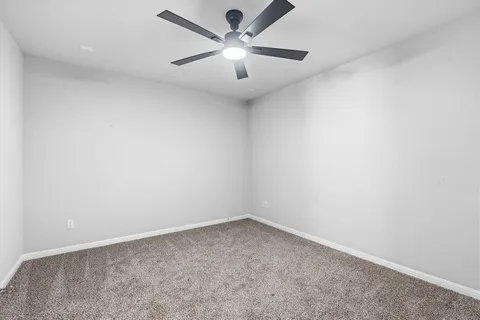 an empty room with a chandelier fan and windows