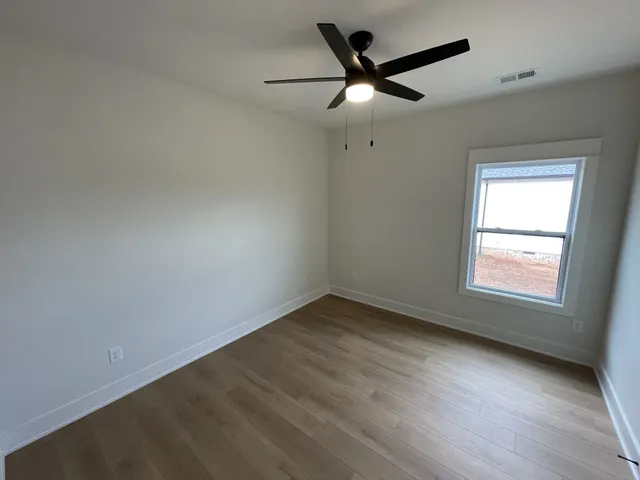 an empty room with a window and a fan
