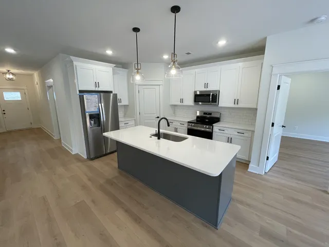 a large white kitchen with a refrigerator a oven a sink and a stove