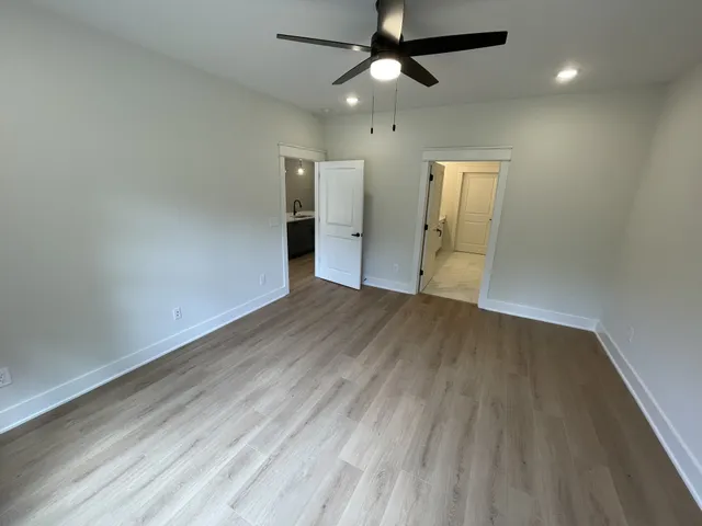 an empty room with wooden floor ceiling fan and windows