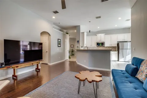a living room with stainless steel appliances kitchen island granite countertop furniture and a flat screen tv