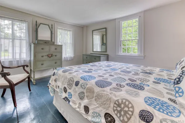 a bedroom with a bed next to a window with a chair