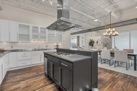 a kitchen with stainless steel appliances granite countertop a stove oven a dining table and chairs with wooden floor