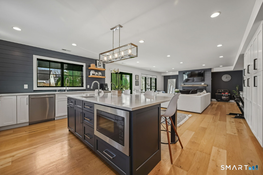 187 Catherine Terrace Fairfield, CT 06824 - Photo 4 of 40 Expansive open concept living with wide plank floors, Quartz-topped striking white cabinets, a wall of built-in storage and wide, lateral gas fireplace.