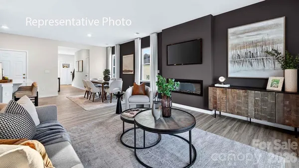a living room with furniture a flat screen tv and kitchen view