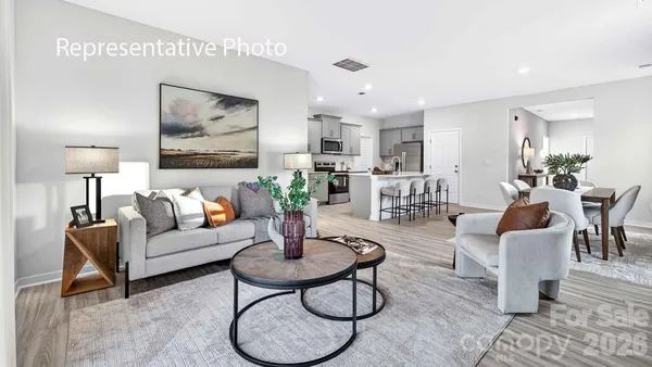 a living room with furniture potted plant and kitchen view