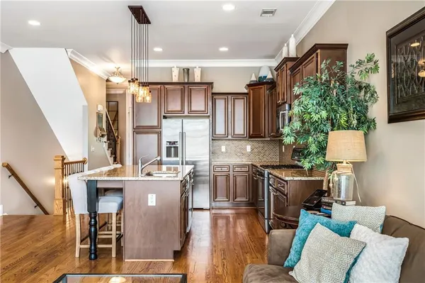 a living room with stainless steel appliances kitchen island granite countertop furniture wooden floor and a kitchen view