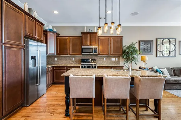 a kitchen with stainless steel appliances granite countertop a stove a refrigerator a kitchen island a dining table and chairs