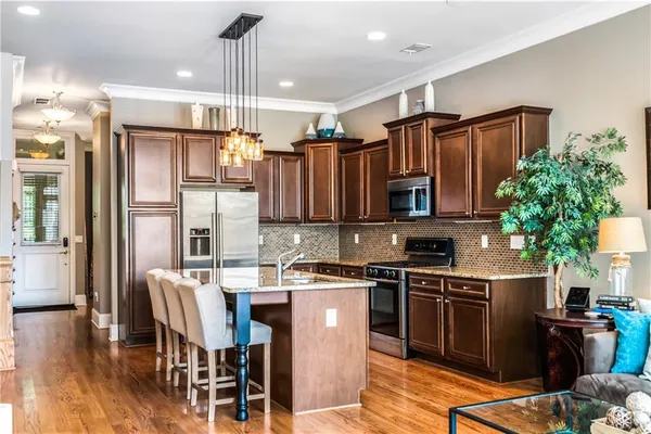 a kitchen with stainless steel appliances granite countertop a stove refrigerator and a view of living room