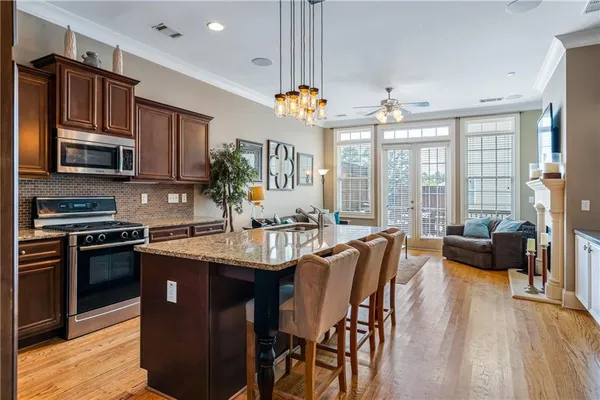 a kitchen with stainless steel appliances granite countertop a stove a refrigerator a sink dishwasher a dining table and chairs with wooden floor