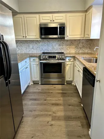 a kitchen with granite countertop a sink stove and refrigerator