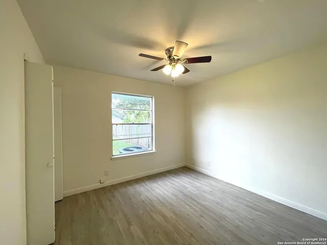a view of empty room with wooden floor and fan
