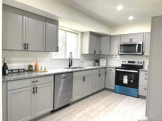 a kitchen with granite countertop a sink stainless steel appliances and cabinets