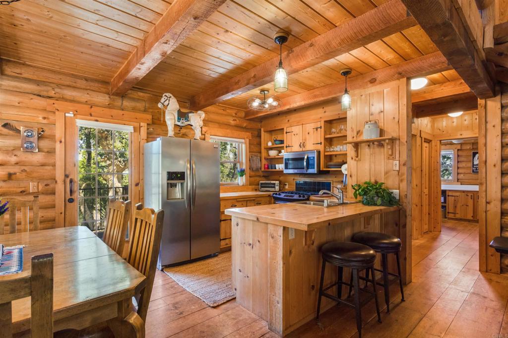 33480 Bailey Meadow Road Palomar Mountain, CA 92060 - Photo 17 of 51 a kitchen with stainless steel appliances a stove a refrigerator a dining table and chairs with wooden floor