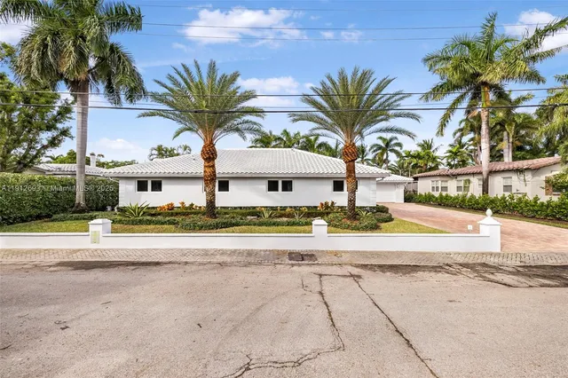 a view of a house with a yard and palm trees