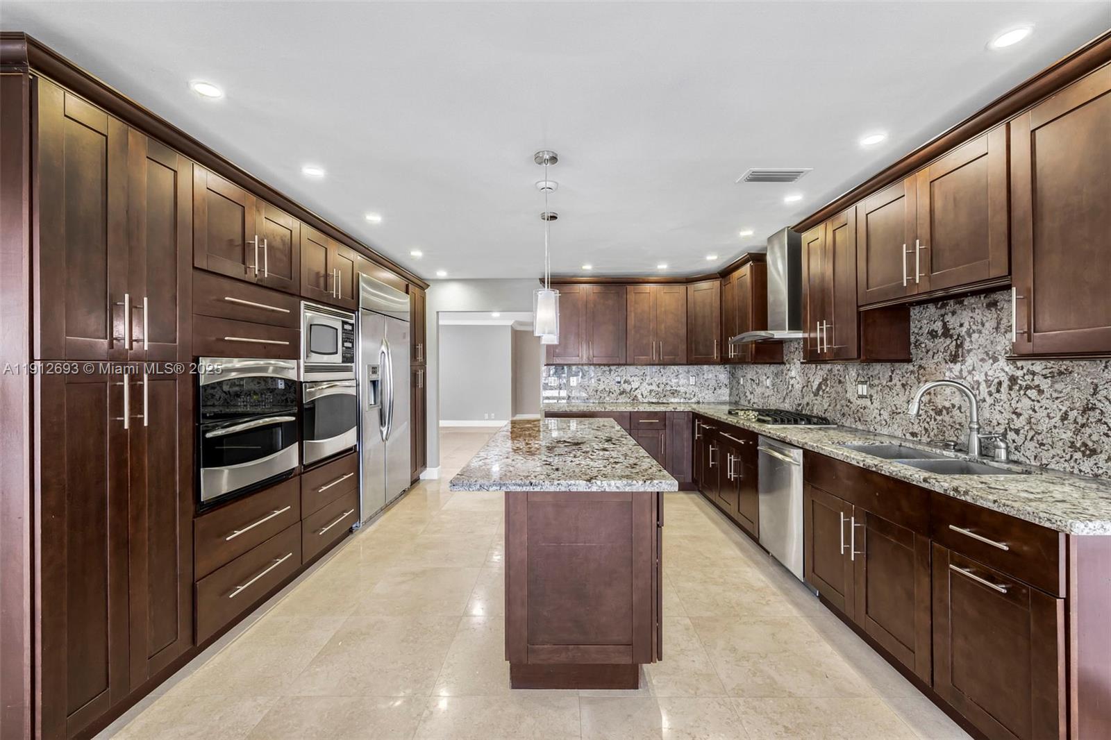 633 Solar Isle Drive Fort Lauderdale, FL 33301 - Photo 50 of 57 a large kitchen with stainless steel appliances wooden cabinets and a stove top oven