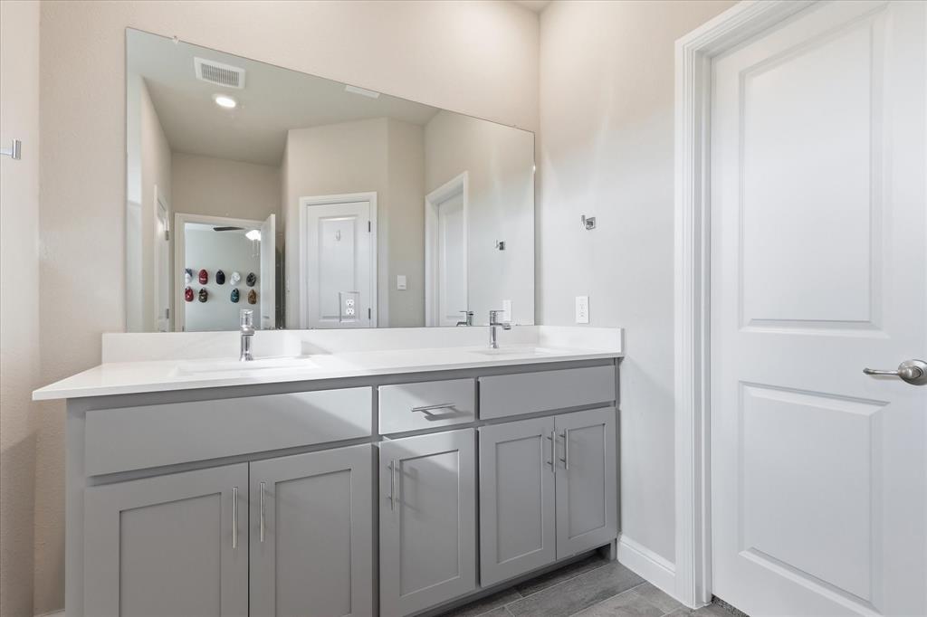 141 Medina Lane Rhome, TX 76078 - Photo 21 of 36 Dual sink vanity with light gray cabinetry, chrome hardware, white countertop, and expansive mirror