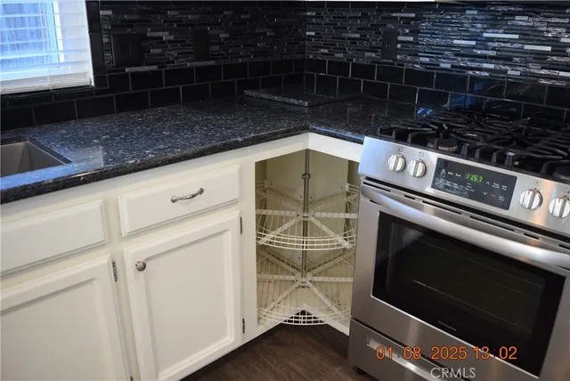a kitchen with granite countertop a sink a stove and cabinets