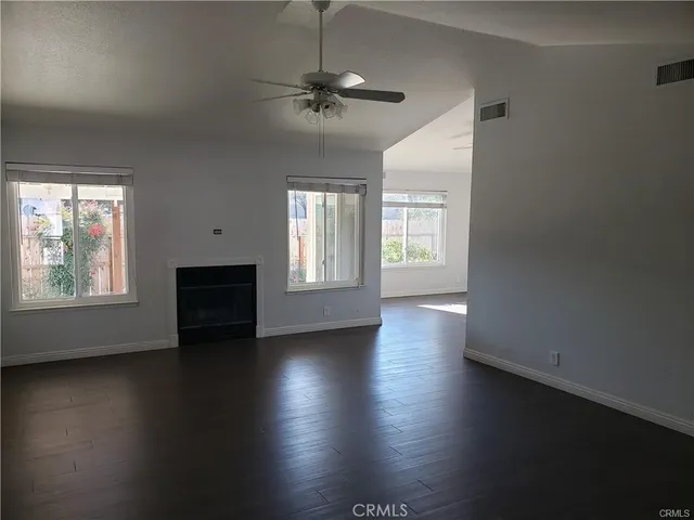 an empty room with wooden floor chandelier and windows
