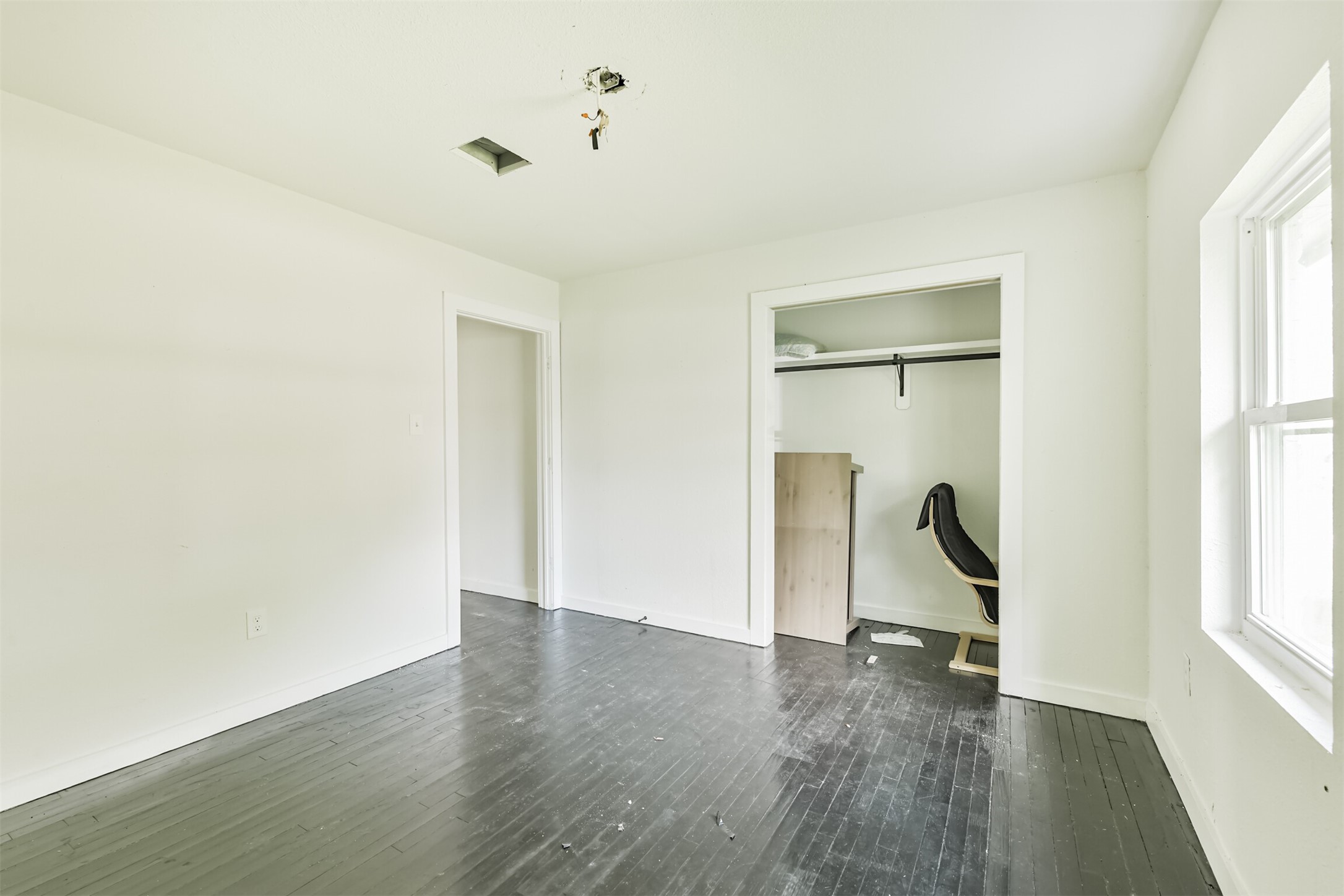 209 Leago Street Houston, TX 77022 - Photo 18 of 24 This room features a minimalist design with white walls and dark hardwood floors. It includes a closet space and a window for natural light. The room appears ready for customization to suit personal preferences.