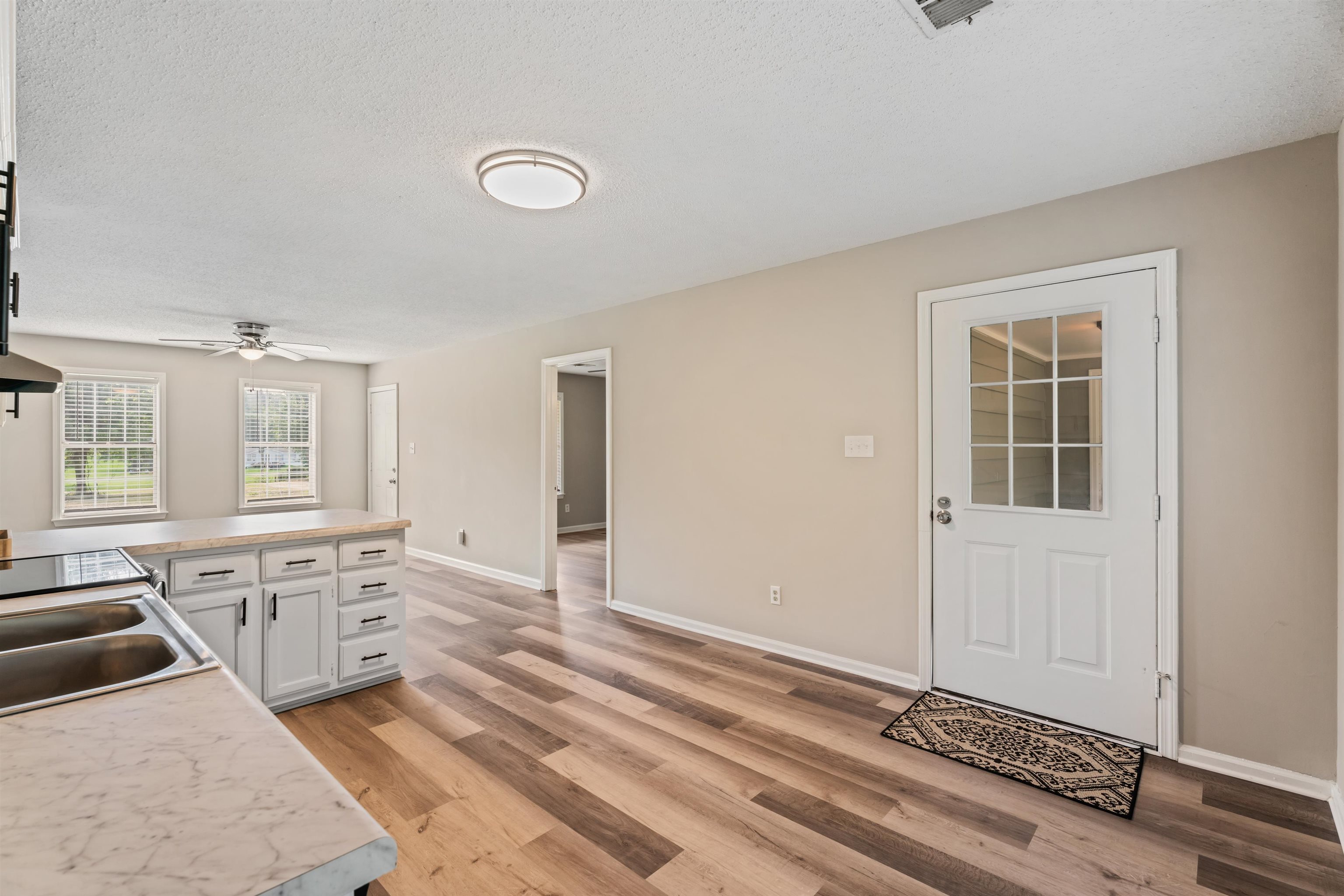 3282 Sunnyside Road Brighton, TN 38011 - Photo 11 of 24 Kitchen with ceiling fan, white cabinets, sink, light hardwood / wood-style floors, and a textured ceiling