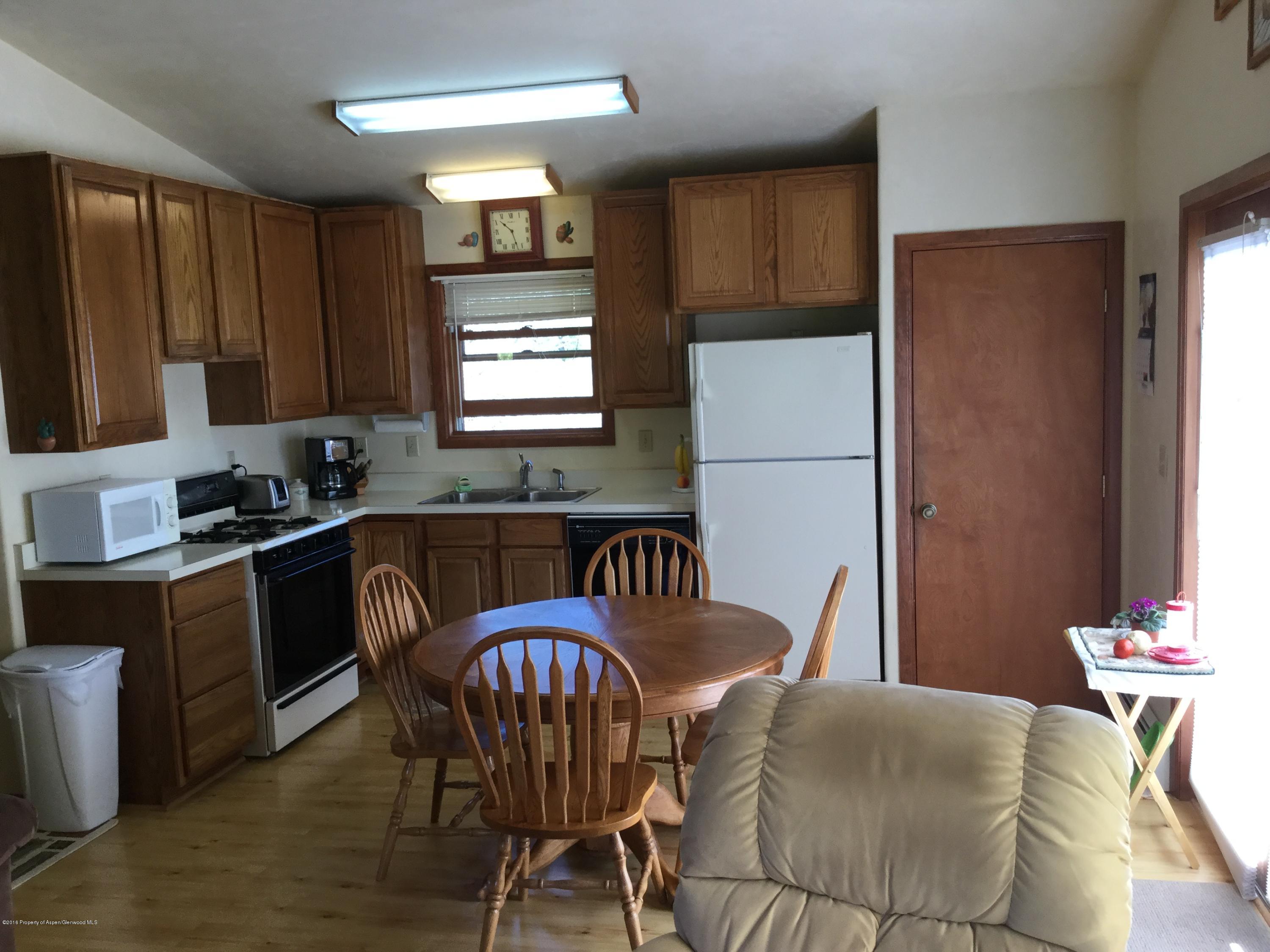 4112 County Road 226 Rifle, CO 81650 - Photo 8 of 34 a kitchen with granite countertop a refrigerator a stove a sink dishwasher with a dining table and chair