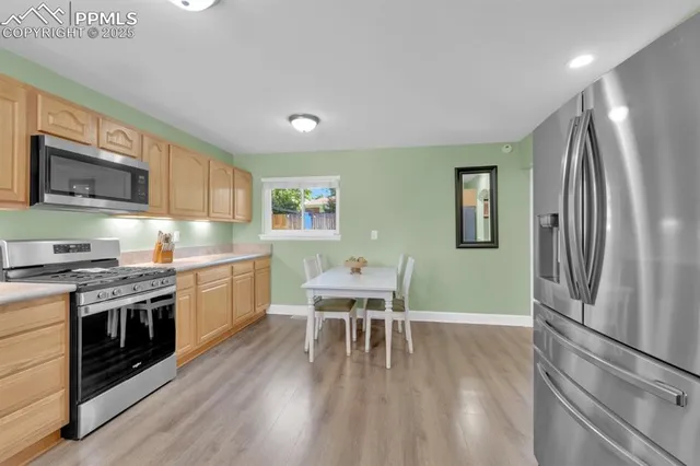 a kitchen with stainless steel appliances granite countertop a stove top oven a sink dishwasher a dining table and chairs with wooden floor