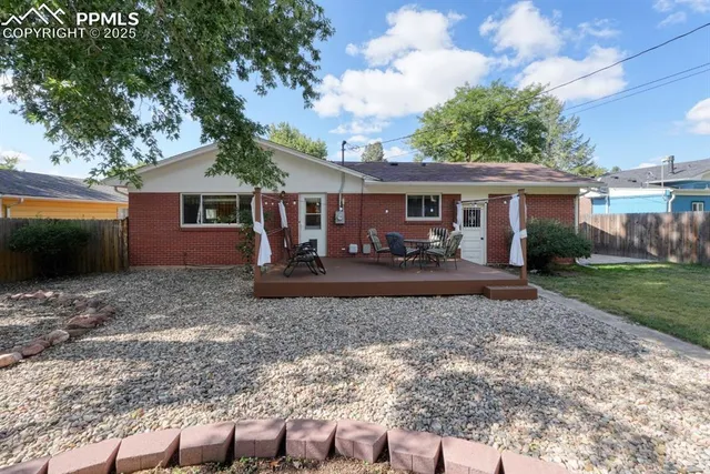 a view of a patio with table and chairs potted plants and floor to ceiling window